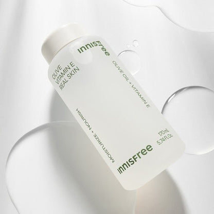 Frosted bottle of moisturizing skin toner with olive oil and vitamin E ingredients on white surface with liquid drops
