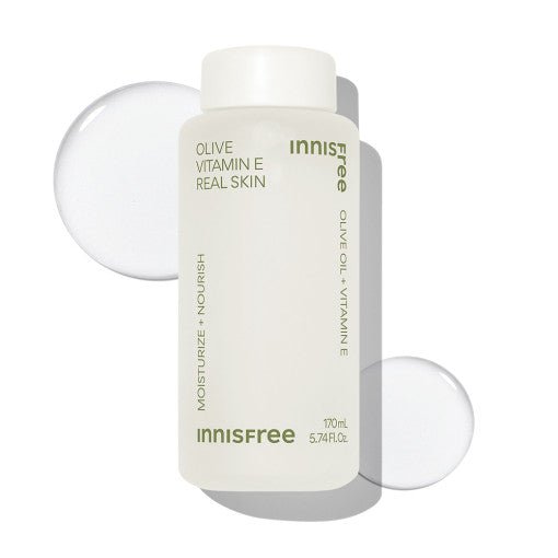 Matte white bottle of Olive Vitamin E Real Skin with clear lotion drops on a bright white background