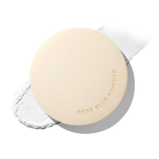 Round beige compact of pore blur powder with smooth matte finish and subtle embossed lettering on white background