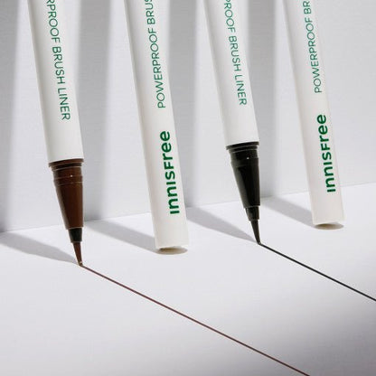 Two innisfree Powerproof Brush Liners with precise brush tips drawing sharp brown and black lines on white surface