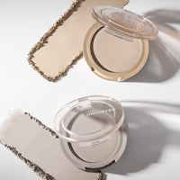 Two open powder compacts with natural-toned shading powders and smooth texture on a white surface