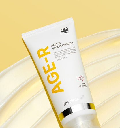 medicube AGE-R Vita K Cream 100ml in white tube with yellow text promoting redness relief on a yellow background