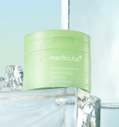 medicube Exosome Cica Calming Pad 150ml/100 Pads in green jar with gentle exfoliation on ice background