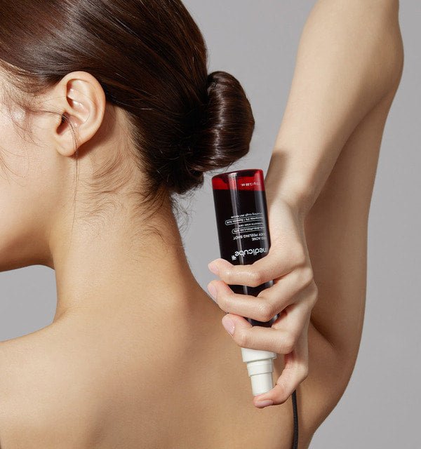medicube Red Acne Body Peeling Shot 110g held behind back demonstrating easy application for effective peeling care