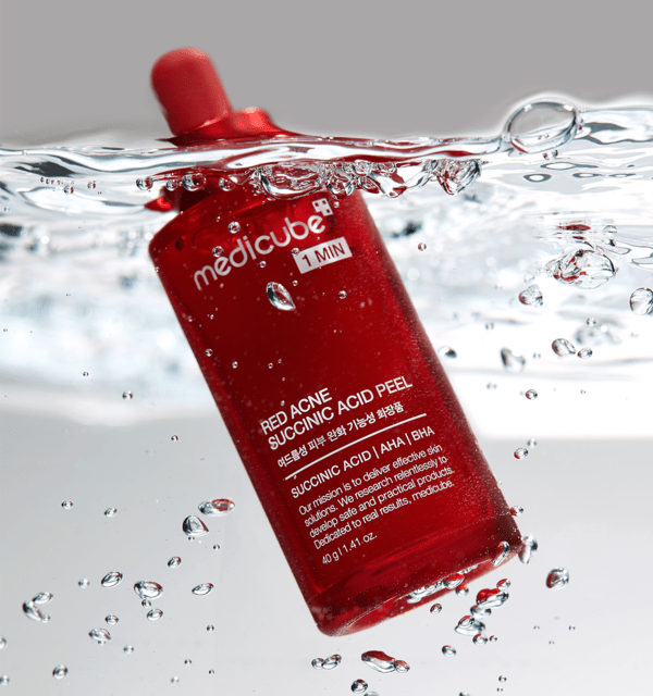 medicube Red Acne Succinic Acid Peel 40g bottle submerged in water with bubbles, acne-clearing skincare product