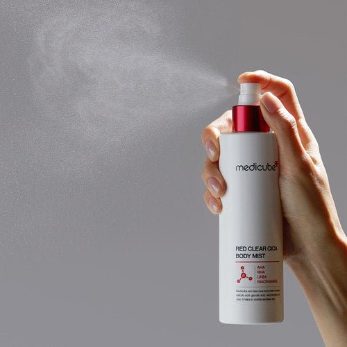 medicube Red Clear Cica Body Mist 200ml being sprayed for clear skin with fine mist in white and red bottle