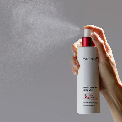 medicube Red Clear Cica Body Mist 200ml being sprayed for clear skin with fine mist in white and red bottle