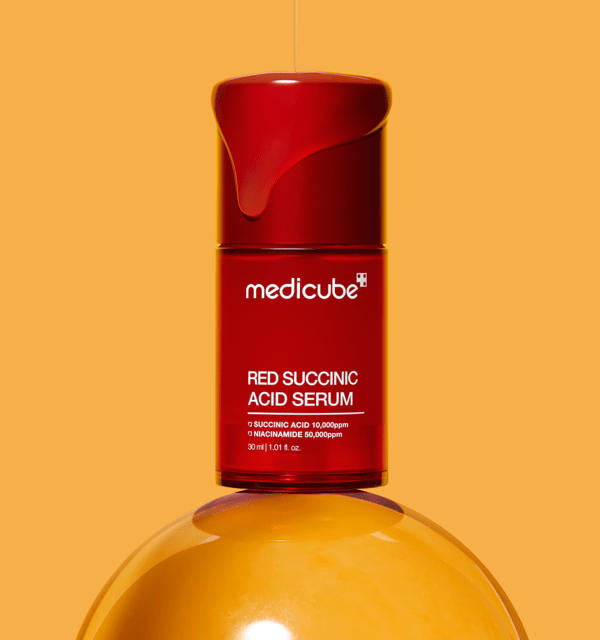 medicube Red Succinic Acid Serum 30ml in red bottle with drop of serum above on orange background for acne relief
