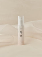 Minimalist beige bottle of ginseng sun serum with a clear pump cap for lightweight UV protection on soft fabric background
