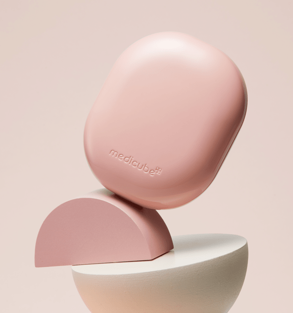 medicube Pro Glutathione Glow Cushion SPF50 15g in soft pink case balanced on abstract geometric shapes