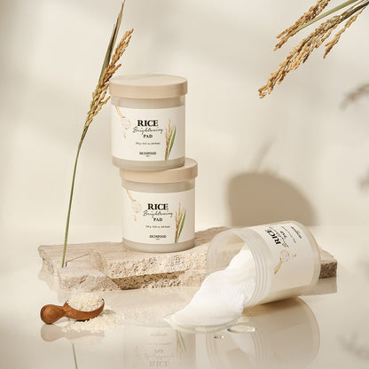 Two beige-lidded jars stacked and one jar tipped over with white brightening pads spilling out on stone surface