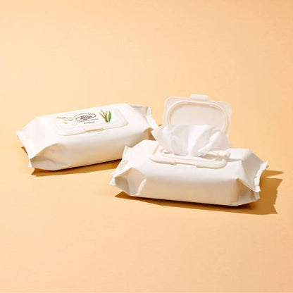 Two white packs of cleansing tissues with one opened showing soft white wipes on beige background