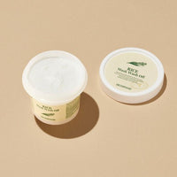 Open jar of brightening rice mask wash off with textured cream beside matching lid on beige background
