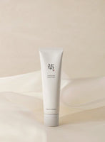 Minimalist white squeeze tube of hydrating cream with subtle Korean lettering on a soft beige fabric background