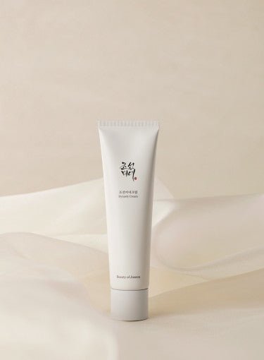 Minimalist white squeeze tube of hydrating cream with subtle Korean lettering on a soft beige fabric background