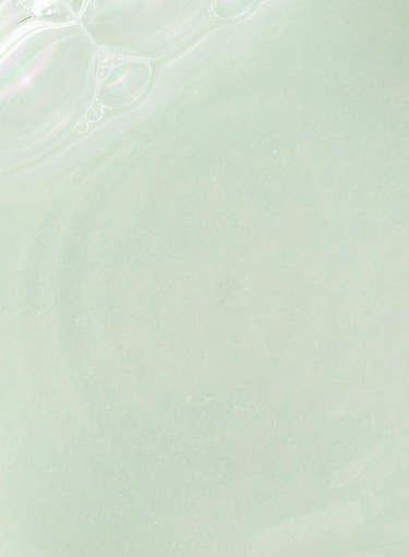 Close-up of light green translucent liquid texture with subtle glossy highlights on smooth surface