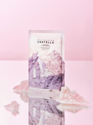 Facial clarifying mask sachet with purple mountain design and pink crystal accents on reflective surface
