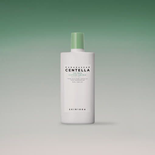 White bottle with green cap of soothing sun milk featuring centella extract and high SPF protection on gradient green background