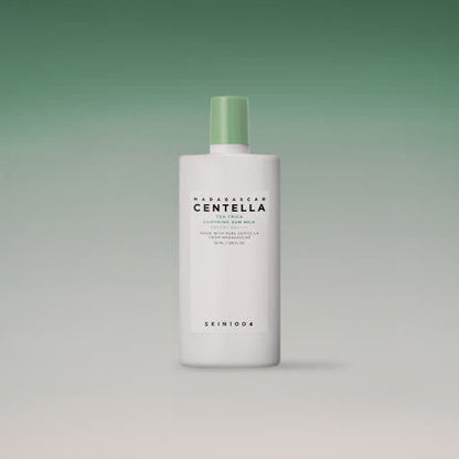 White bottle with green cap of soothing sun milk featuring centella extract and high SPF protection on gradient green background