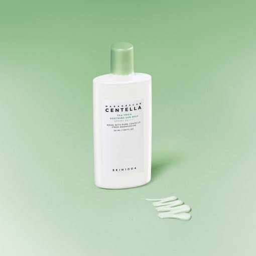 White bottle of soothing sun milk with green cap and product swatch on pale green background
