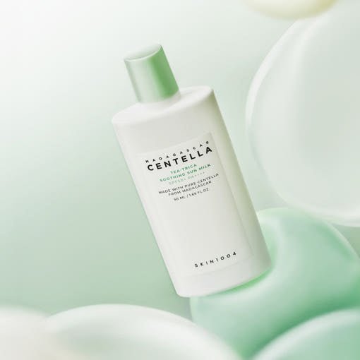 White bottle of soothing sun milk with green cap and minimalist label set against soft pastel background