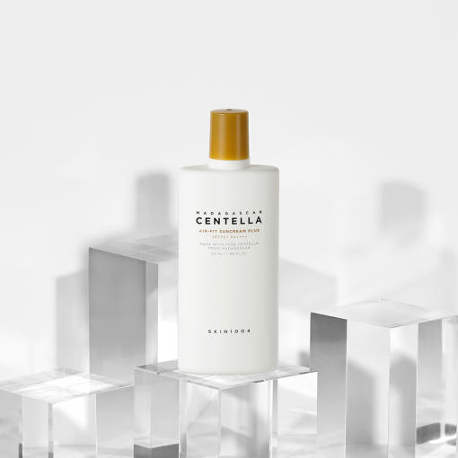 White suncream bottle with gold cap labeled for broad spectrum protection on clear geometric blocks background