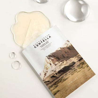 Sheet mask packet with natural landscape design and translucent gel mask on white background with hydration droplets