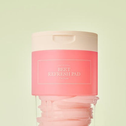Pink container of refreshing beet skincare pads with white lid and visible cotton pads inside against pale green background