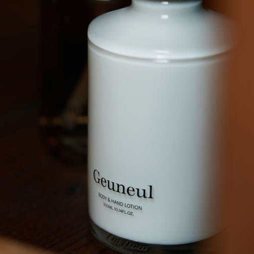 Minimalist white bottle of body and hand lotion with black text label on a warm wooden surface background