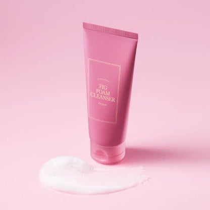 Pink tube of gentle fig foam cleanser standing with foamy white lather on soft pink background