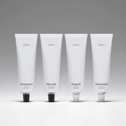 Four minimalist white tubes of hand cream with black and white caps arranged in a row on a neutral background