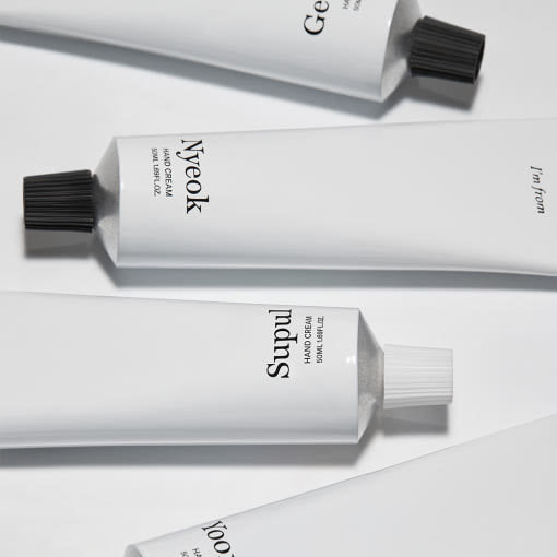 Four minimalist white tubes of moisturizing hand cream with black twist caps on a light background