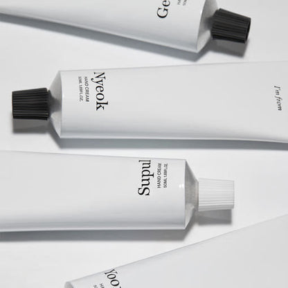 Four minimalist white tubes of moisturizing hand cream with black twist caps on a light background