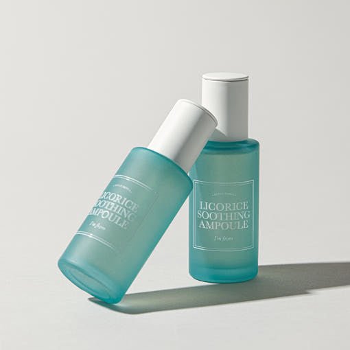 Two frosted blue glass bottles of soothing ampoule with white caps on a light neutral background