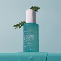 Blue translucent ampoule bottle with white cap and green leaf accents on soft blue background