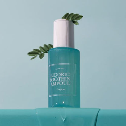 Blue translucent ampoule bottle with white cap and green leaf accents on soft blue background
