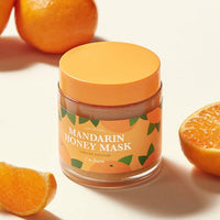 Jar of hydrating mandarin honey mask with bright orange lid surrounded by fresh mandarin oranges segments