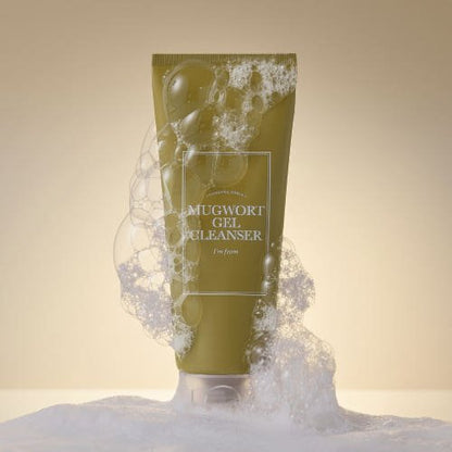 Olive green tube of gentle gel cleanser surrounded by white foamy bubbles on a neutral background
