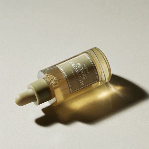 Glass dropper bottle of soothing mugwort serum casting soft shadow on beige surface
