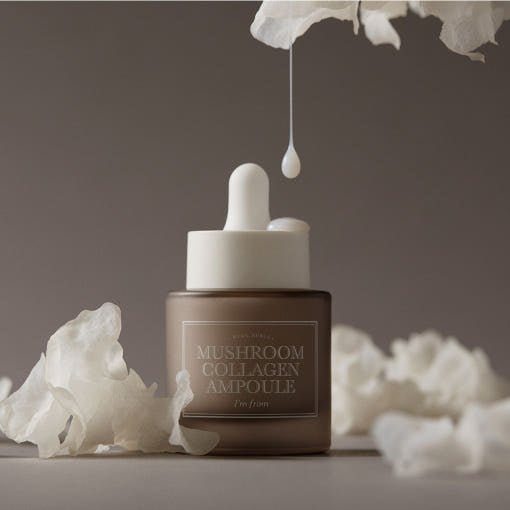 Frosted brown glass dropper bottle with creamy mushroom collagen ampoule and white textured background elements