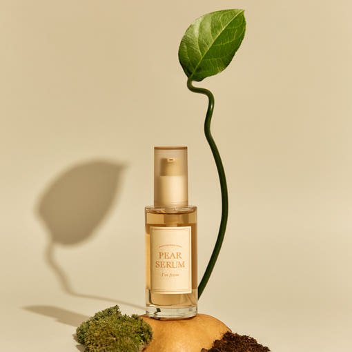 Glass pump bottle of hydrating pear serum with natural leaf and organic elements on a neutral background
