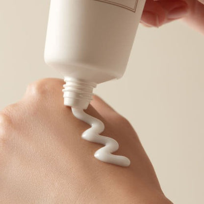 Creamy white peel-off mask being squeezed from a tube onto the back of a hand with smooth skin visible