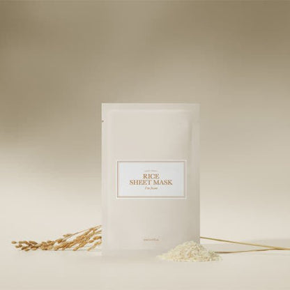 Minimalist rice sheet mask packet with elegant label, accompanied by rice grains and stalk on beige background