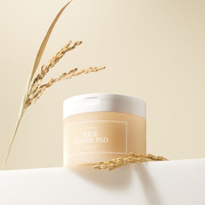Round translucent container of toner pads with natural rice stalks on soft beige background with hydration focus