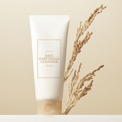 Minimalist white tube of moisturizing facial cleanser with dried rice stalks on soft beige background