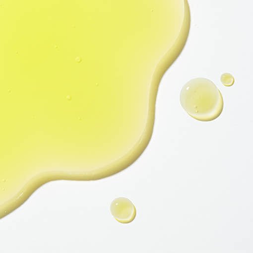 Bright yellow serum droplets with a smooth texture demonstrating brightening skincare benefits on white surface