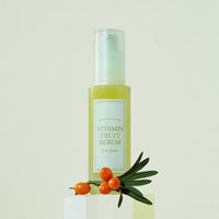 Clear pump bottle of yellow vitamin fruit serum with orange berries and green leaves on pale background