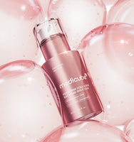 medicube PDRN Pink Collagen Exosome Shot 2000 30ml bottle surrounded by glossy pink translucent bubbles representing enhanced radiance