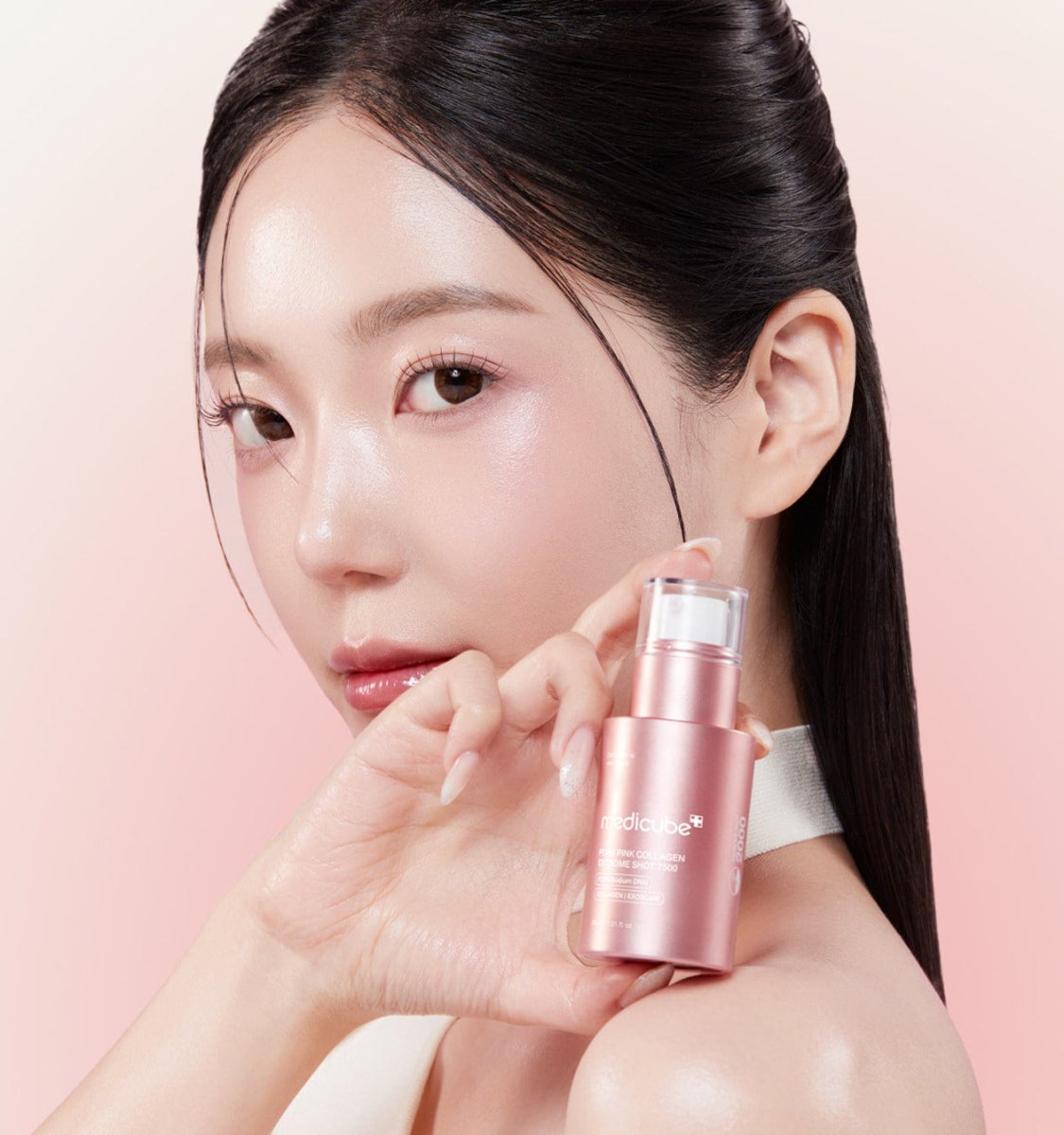 medicube PDRN Pink Collagen Exosome Shot 7500 30ml in rose gold bottle held by woman with glowing skin for cell regeneration