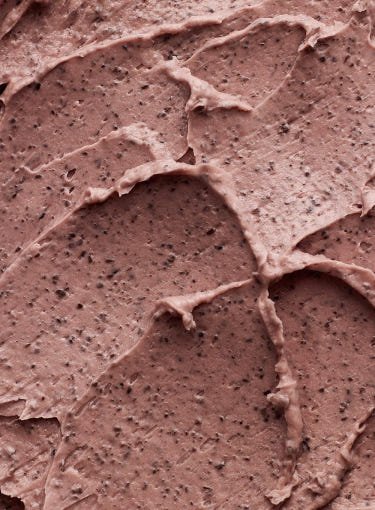 Creamy textured red bean pore mask with visible exfoliating granules on smooth surface close-up